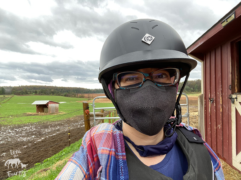 A woman wearing an equestrian helmet and a mask with glasses